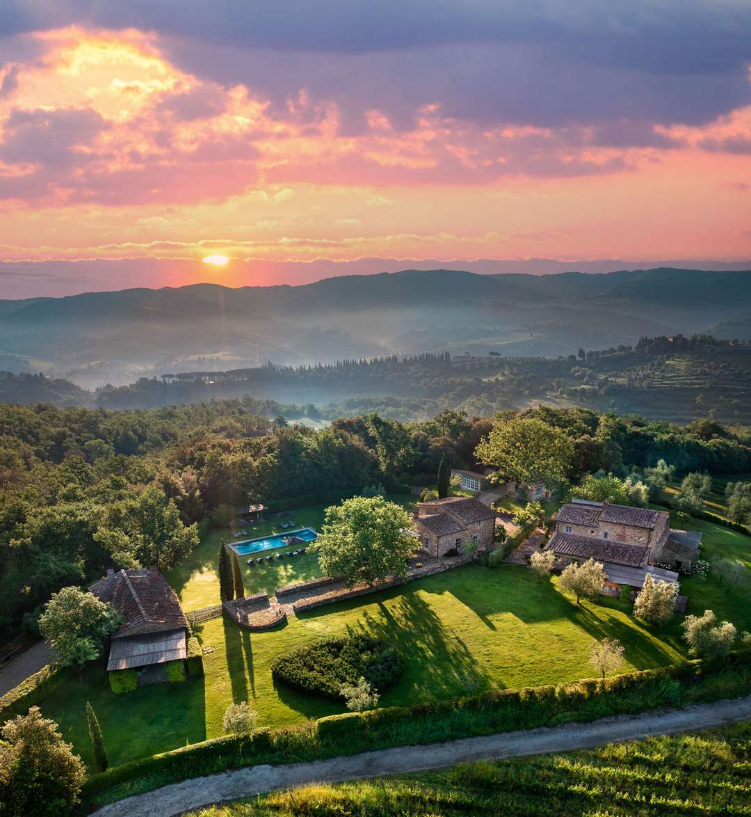 Aerial view of Verdiana estate at sunset, showcasing the luxury Tuscan villa, salt water pool, and rolling vineyard views.