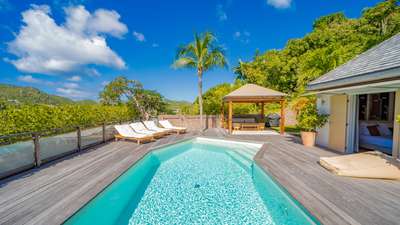 Luxury Caribbean villa terrace featuring a private heated pool, sun loungers, and an elegant gazebo for evening cocktails.