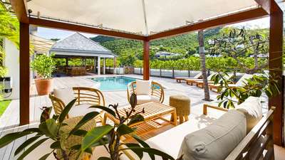 Shaded gazebo lounge overlooking the private heated pool, wooden sun deck, and vibrant tropical hillside views.