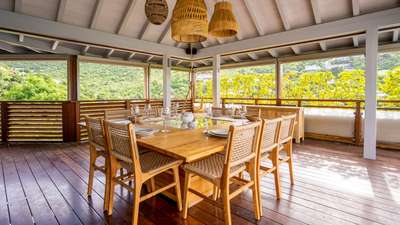 Elegant al fresco dining setup on the expansive covered terrace, surrounded by vibrant tropical vegetation in St-Barths.