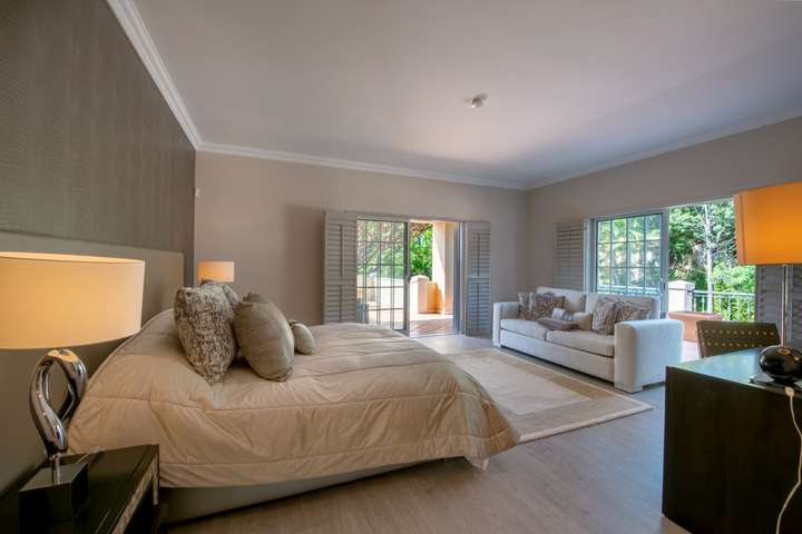 Spacious master suite at Villa Atlantico with a plush bed, cozy seating area, and patio doors opening to a private terrace.