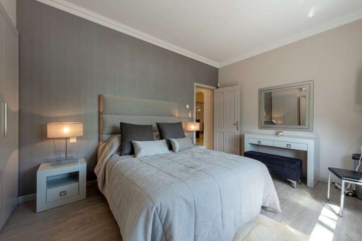 Chic bedroom at Villa Atlantico with a grey upholstered headboard, textured walls, and a sleek white modern vanity desk.