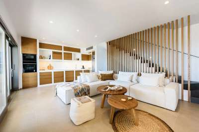 Elegant living room in Paros featuring a white sectional, natural wood accents, and a striking slatted staircase design.