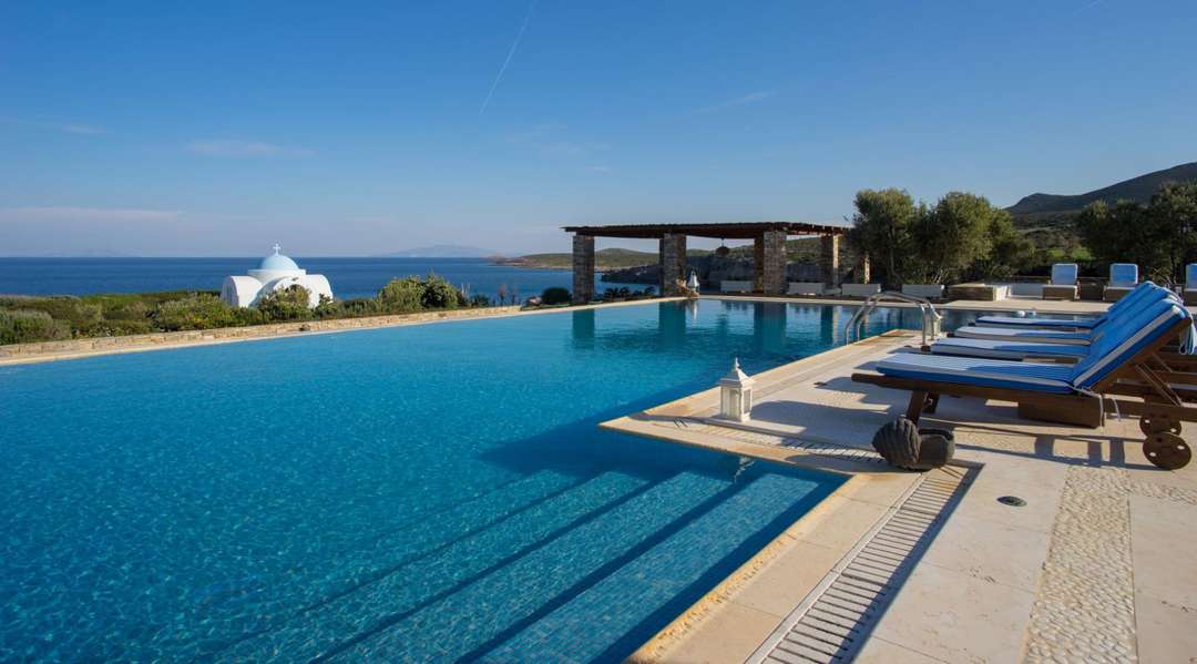 Pristine infinity pool at Villa Atlas in Antiparos, offering panoramic Aegean Sea views and elegant sun loungers.