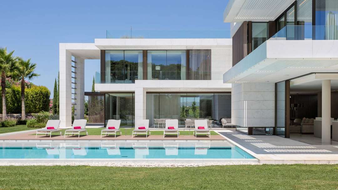 Contemporary luxury at Villa Cavado with a large private pool, sun loungers, and sleek glass facades in Quinta do Lago.