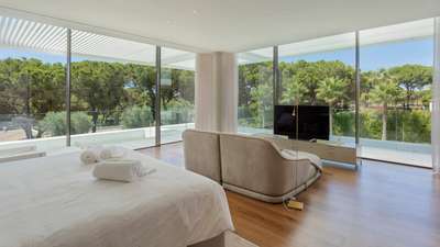 Expansive Primary Suite at Villa Cavado with floor-to-ceiling windows, private lounge area, and stunning golf course views.