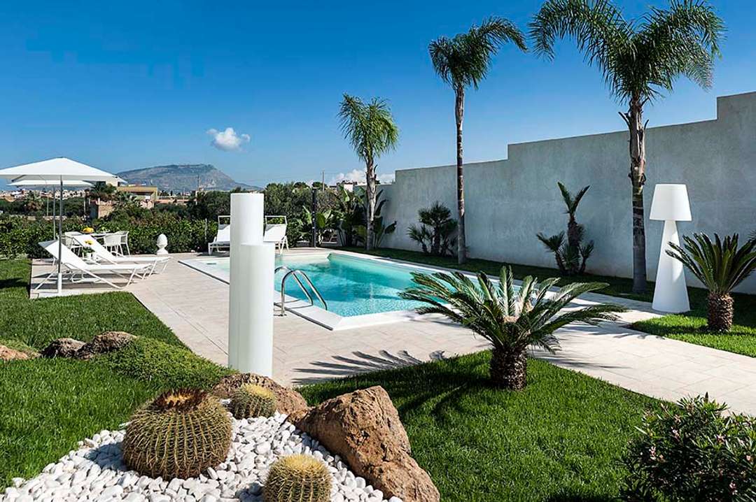 Private pool at Villa della Laguna in Trapani, featuring sun loungers, manicured gardens, and stunning country views.