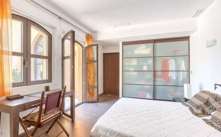 Stylish air-conditioned bedroom with a wooden desk, frosted glass wardrobe, and French doors opening to stunning sea views.
