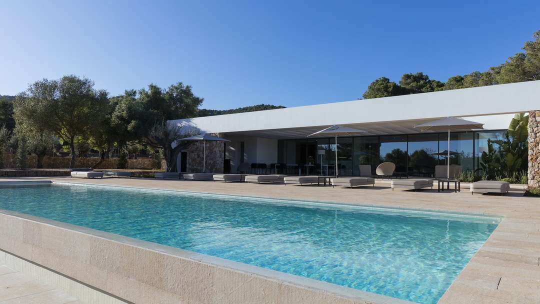 Sparkling private pool at Villa Eclipse with light stone deck, modern white architecture, and tranquil olive grove views.