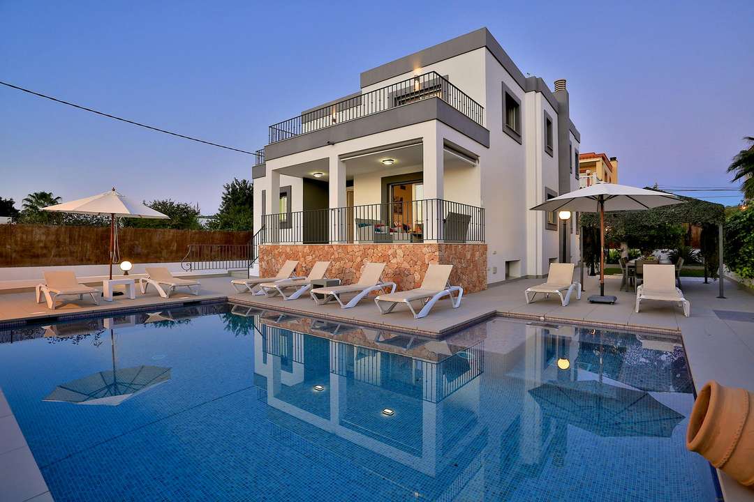 Luxury Villa Encore in Ibiza Town featuring a serene private pool, elegant sun loungers, and modern exterior architecture.
