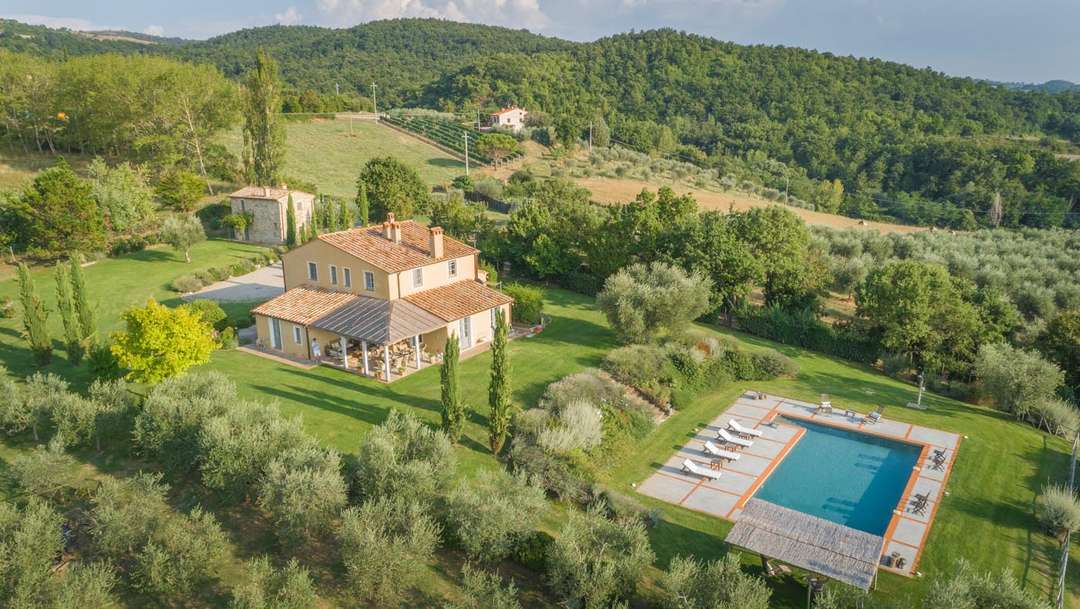 Aerial view of Villa Federico in Tuscany, featuring a private pool, traditional architecture, and stunning olive grove views.