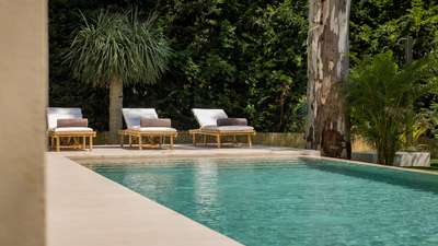 Pristine private swimming pool at Marbella Sands surrounded by a manicured garden and elegant bamboo sun loungers for relaxing.