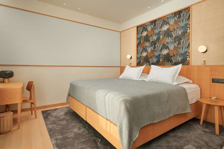 Elegant bedroom at Villa Sapphire with a king-size bed, coastal-inspired patterned headboard, and minimalist wooden desk.