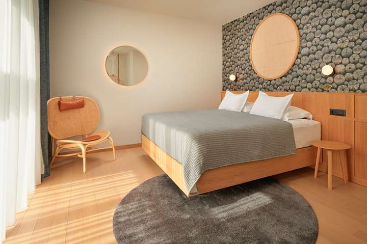 Elegant king bedroom at Villa Sapphire with modern wood furnishings, rattan chair, and bright linear aesthetic in Hvar.