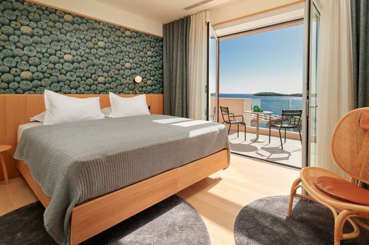 Bright king bedroom at Villa Sapphire featuring patterned wallpaper and terrace access with stunning Adriatic Sea views.