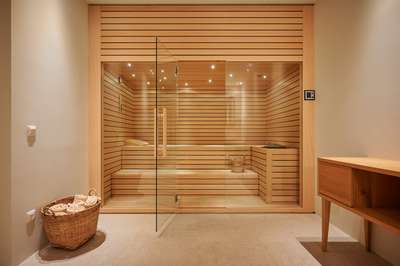 Exclusive in-house private sauna featuring premium wood paneling, glass doors, and a relaxing wellness atmosphere.