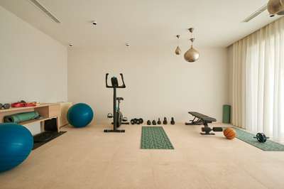 Fully equipped private in-house gym with an exercise bike, free weights, and yoga mats in a bright, modern space.