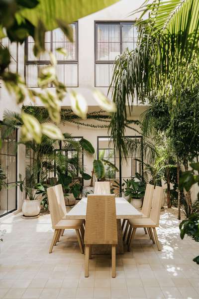 Luxurious alfresco dining in Villa Imperia's courtyard, featuring a stone table, modern chairs, and lush tropical plants.
