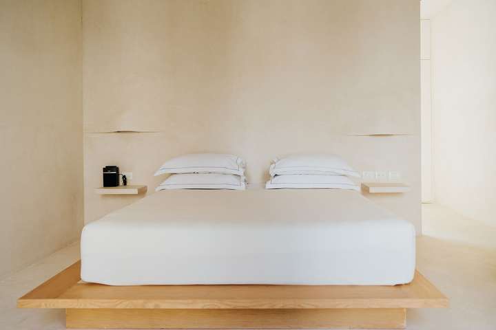 Elegant master suite featuring a minimalist platform bed, crisp white linens, and rustic tropical design at Villa Imperia.