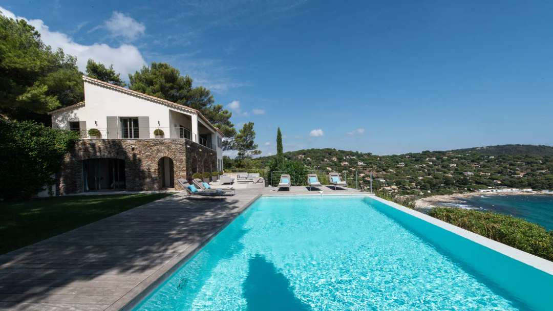 Villa Infinity's stone facade and teak deck terrace with a 12-meter heated infinity pool overlooking the Mediterranean Sea.