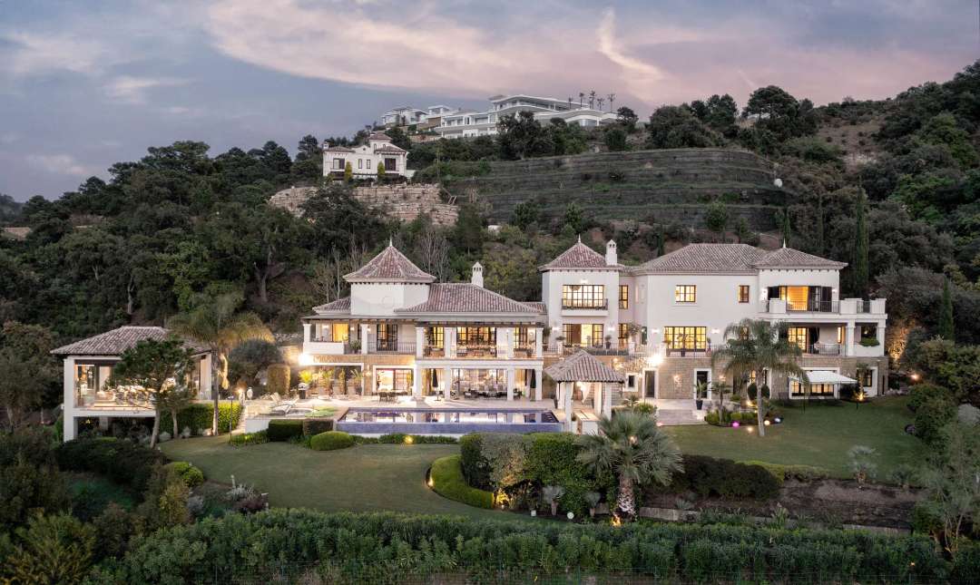 Stunning exterior of Villa La Bambola at dusk, featuring a large pool, elegant terraces, and Serranía de Ronda views.