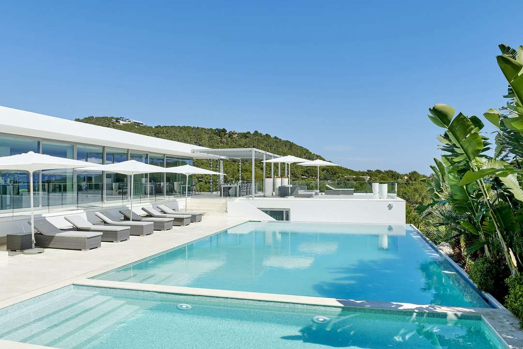 Private infinity pool and sun loungers at Villa La Costa, featuring contemporary design and lush pine forest views in Ibiza.