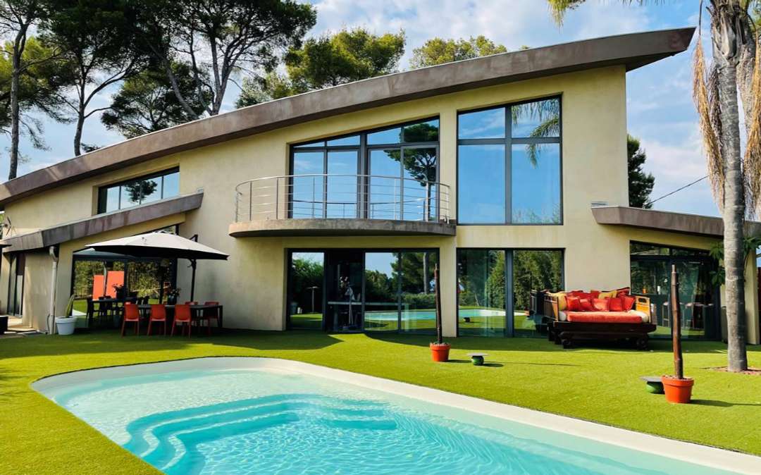 Modern luxury villa rental in Vallauris featuring distinctive architecture, a private pool, and expansive glass windows.