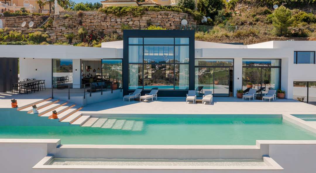 Modern exterior of Villa Loren featuring a stunning private pool, expansive glass windows, and elegant sun loungers.
