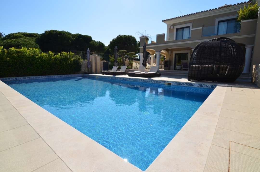 Luxury Algarve villa featuring a large private swimming pool, elegant sun loungers, and a unique woven daybed pod.