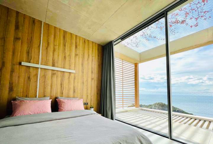 Luxurious bedroom featuring warm wooden paneling and floor-to-ceiling windows with stunning sea views at Villa Panorama.