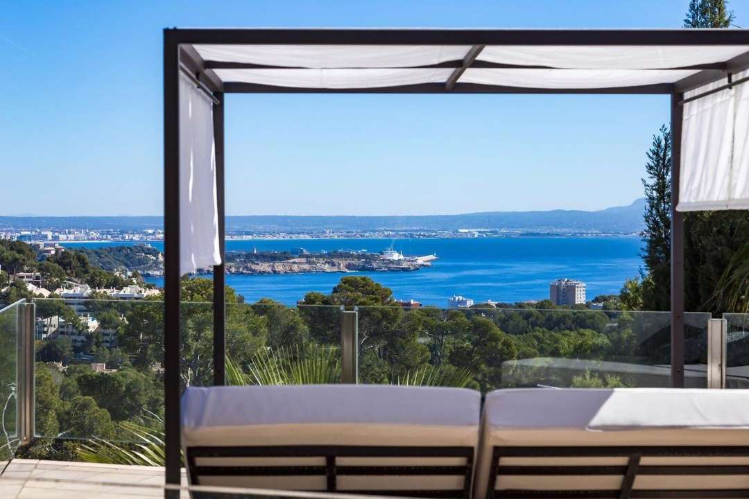 Relax on a shaded daybed with panoramic views of the Mediterranean Sea and Palma Bay at luxury Villa Petunia in Portals Nous.