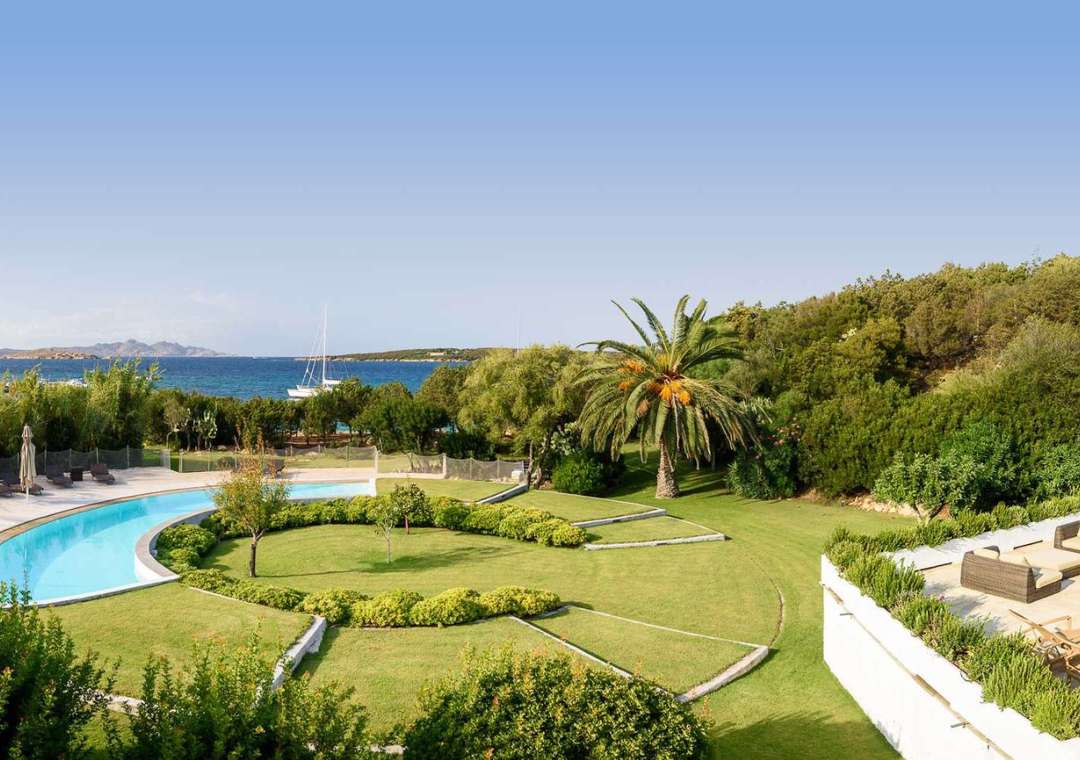 Beachfront swimming pool and manicured grounds at Villa Ricky, offering stunning panoramic ocean views in Costa Smeralda.