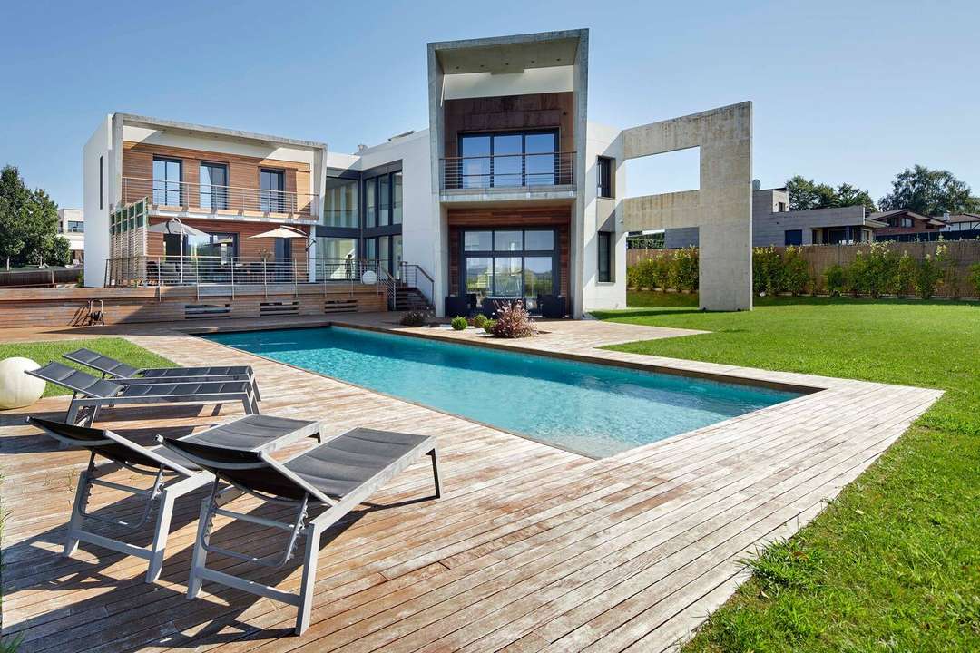 Sleek private pool and wooden deck with sun loungers at a modern luxury villa in San Sebastián with unique architecture.