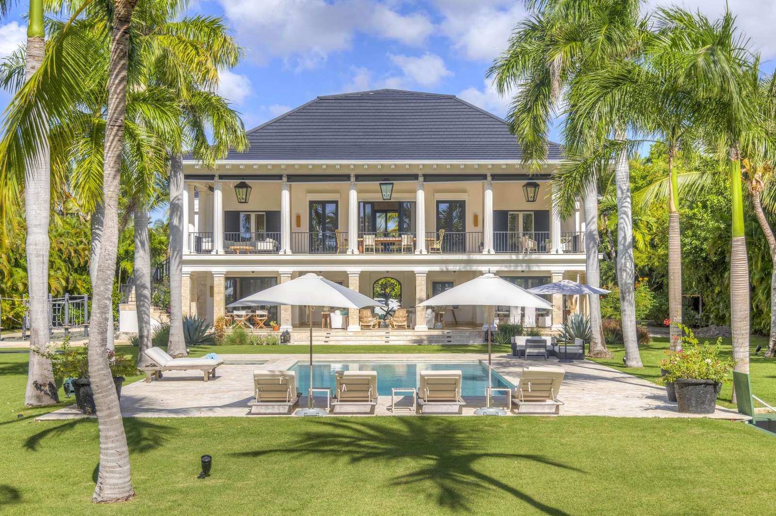 Villa Serenity, Punta Cana – Elegant exterior of Villa Serenity in Punta Cana, featuring a pristine private pool, sun loungers, and lush palm trees.