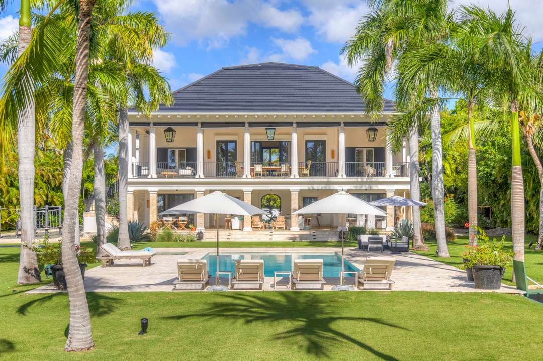 Villa Serenity in Punta Cana features a stunning private pool, manicured gardens, and elegant two-story architecture.