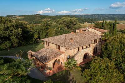 Rustic architecture of Villa Serenzia, a luxury farmhouse featuring a stone facade, terracotta roof, and arched loggia.