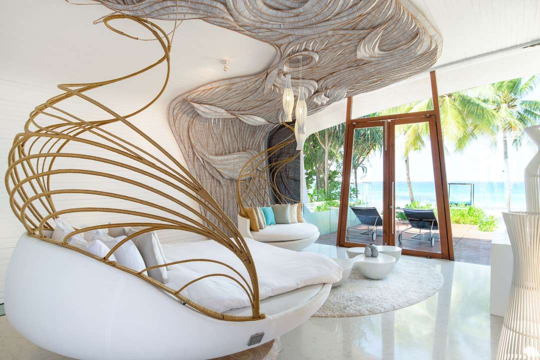 Luxury beachfront bedroom at Villa Siam featuring a unique woven canopy bed, elegant white interiors, and stunning sea views.