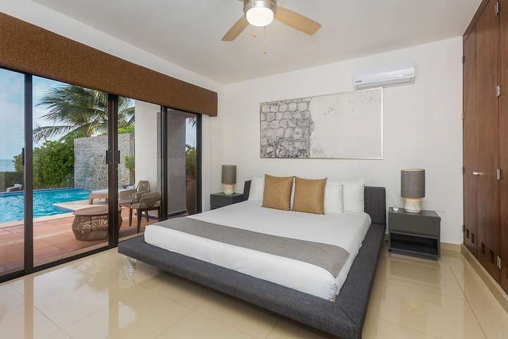 Luxurious master suite at Villas Solil featuring a king bed and sliding doors opening to a private pool and ocean views.