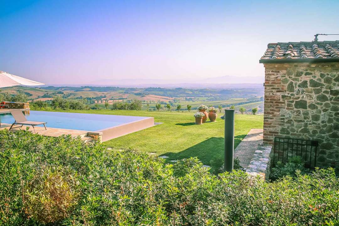 Private infinity pool at Vineranda with panoramic Val d'Orcia countryside views and traditional Tuscan stone architecture.