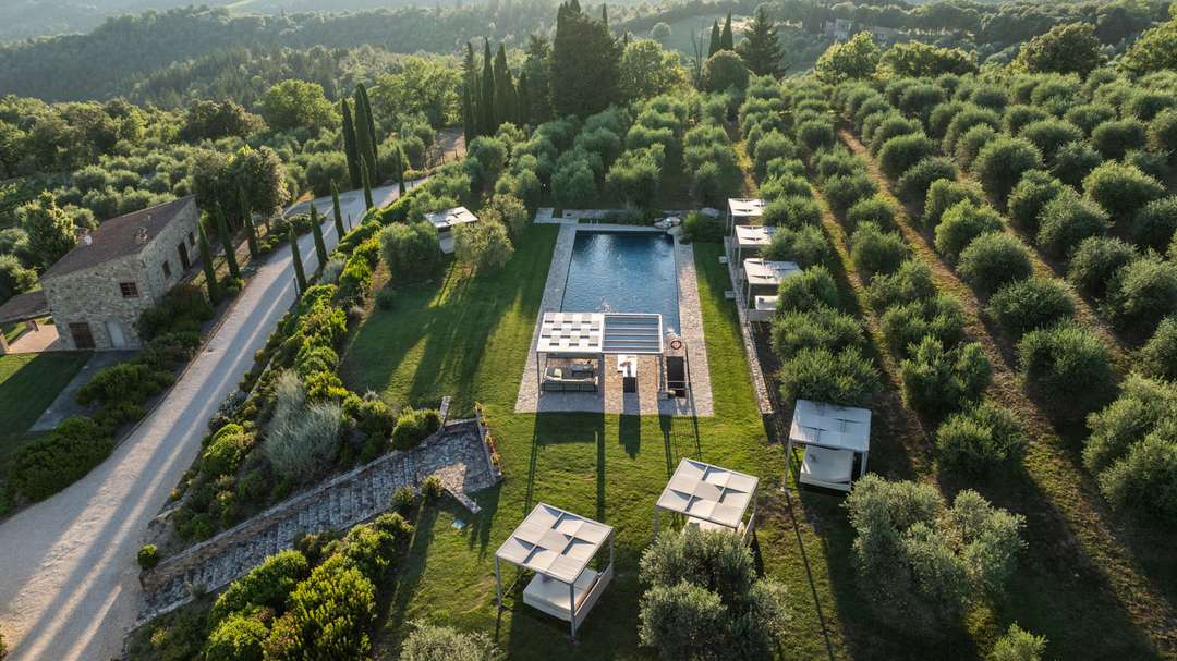 Aerial view of Vinia's 16-meter panoramic pool, surrounded by manicured gardens and olive groves in the Chianti countryside.