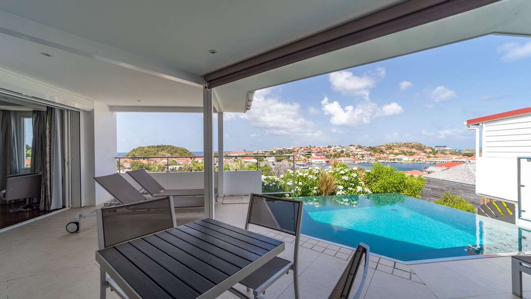 Alfresco dining on the covered terrace by the infinity pool with panoramic Gustavia harbor views at Villa Wastra.