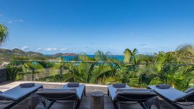 Plush sun chairs on the expansive terrace, perfectly oriented towards endless blue ocean views and St. Jean bay in St. Barths.