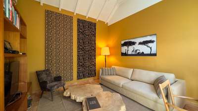 Elegant private retreat in Villa Xanadu with warm yellow walls, natural wood slice tables, and sophisticated African artwork.