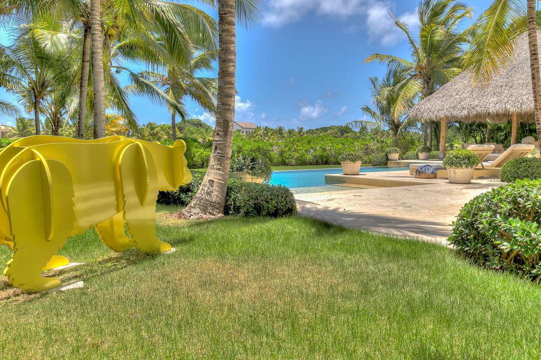 Striking yellow bear sculpture on the manicured lawn by the private pool at Villa Yellow Bear, surrounded by tropical gardens.
