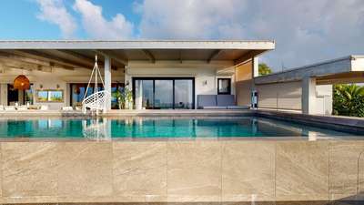 Elegant stone-edged infinity pool at Villa Yolo, overlooking a covered terrace with a hanging chair and comfortable daybed.