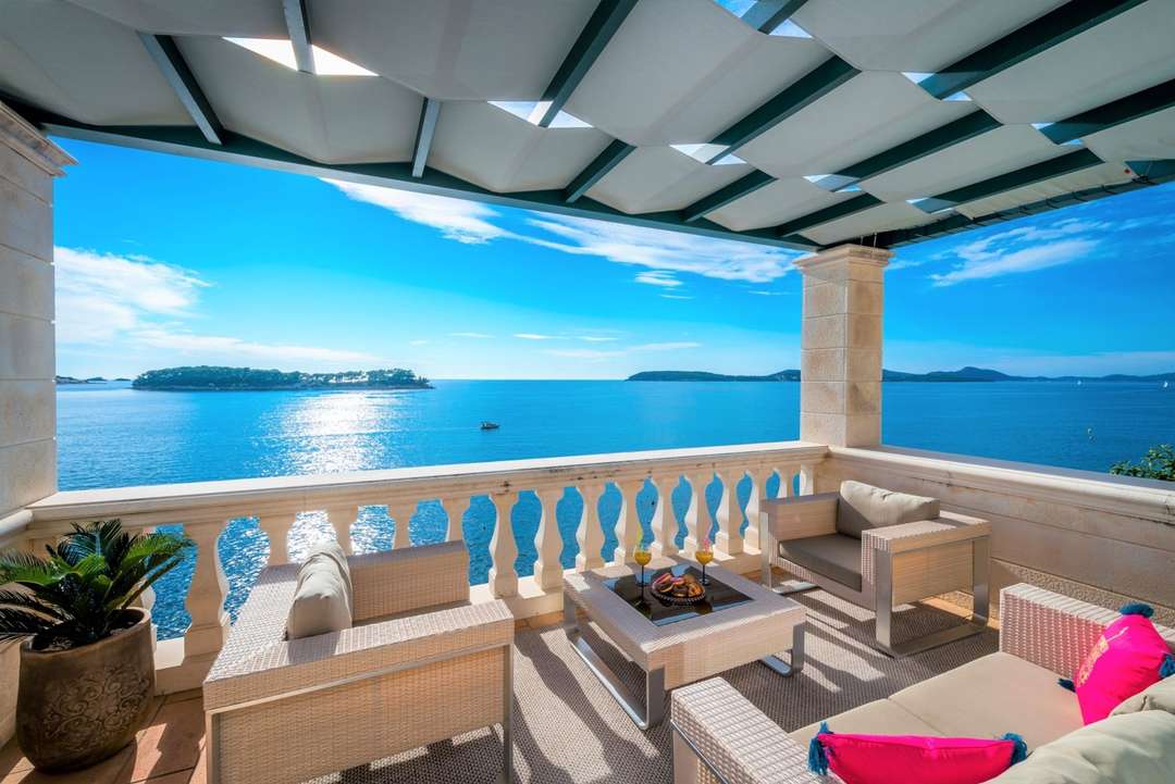 Elegant covered terrace at Zion Dubrovnik featuring woven lounge seating, stone balustrades, and panoramic Adriatic Sea views.